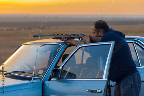 The guy shoots cartridges with a gun in nature, The hunter shoots at the target at sunset 