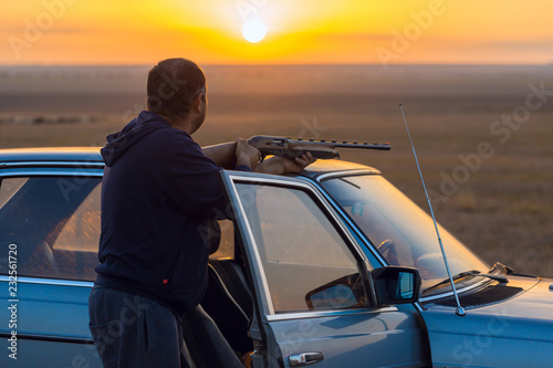 The guy shoots cartridges with a gun in nature, The hunter shoots at the target at sunset 