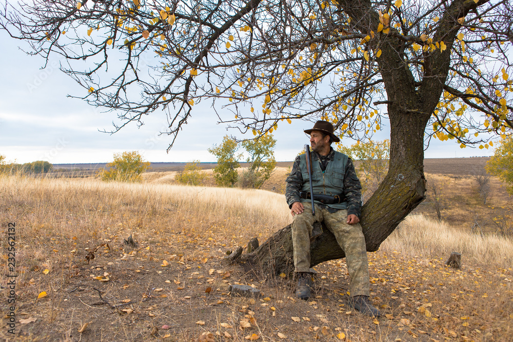 Hunter with a hat and a gun in search of prey in the steppe	