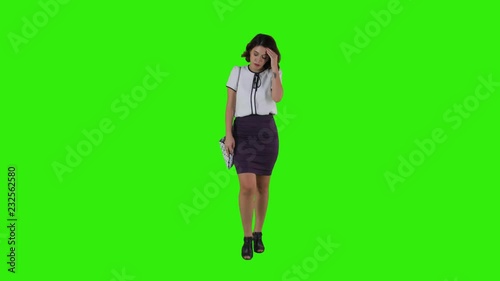 Stylish sad woman walking while having a headache over a green screen in a full frontal shot.