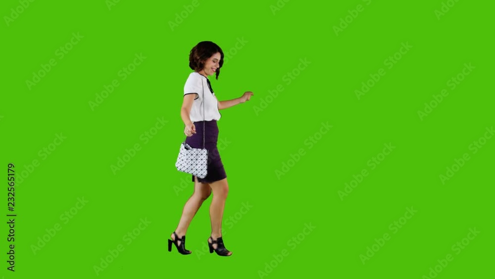 Stylish happy woman walking and dancing over a green screen in a full side shot after receiving some incredible news. Stylish happy woman walking and dancing over a green screen in a full side shot after receiving some incredible news.