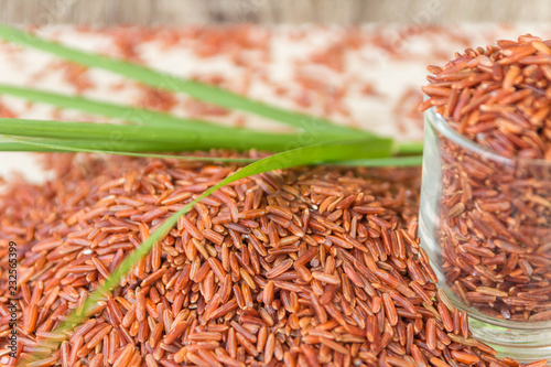 Red rice or Bruwn rice piled on a wooden floor and in a small glass photo