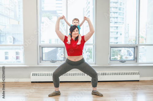 Young woman with child doing workout in gym class to loose baby weight. Child-friendly fitness for mothers with kids toddlers. Lifestyle concept of parent activity.