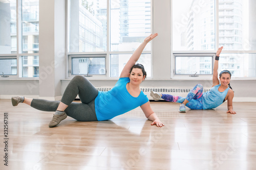 Group of two young women doing workout in gym class indoors to loose weight. Lifestyle healthy concept for active modern women adults.