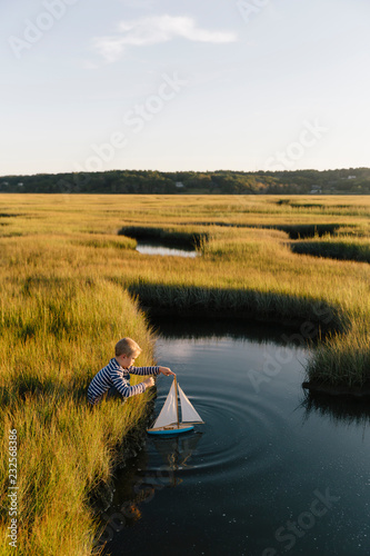 Boy Playing with Toy Sailboat Outdoors photo