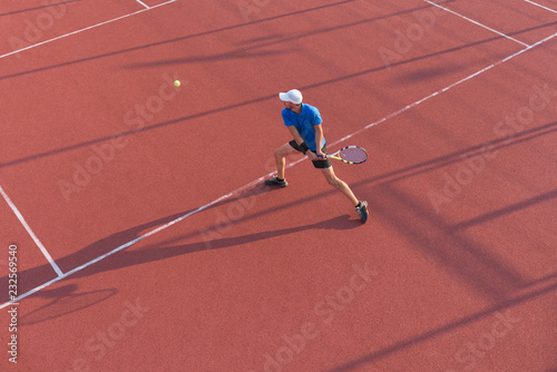 Male tennis player hitting the ball with backhand technique