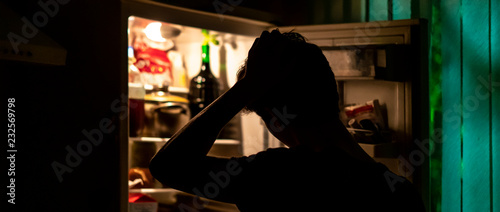 Принти на полотні man standing near the opened fridge to pick some food at night at home f