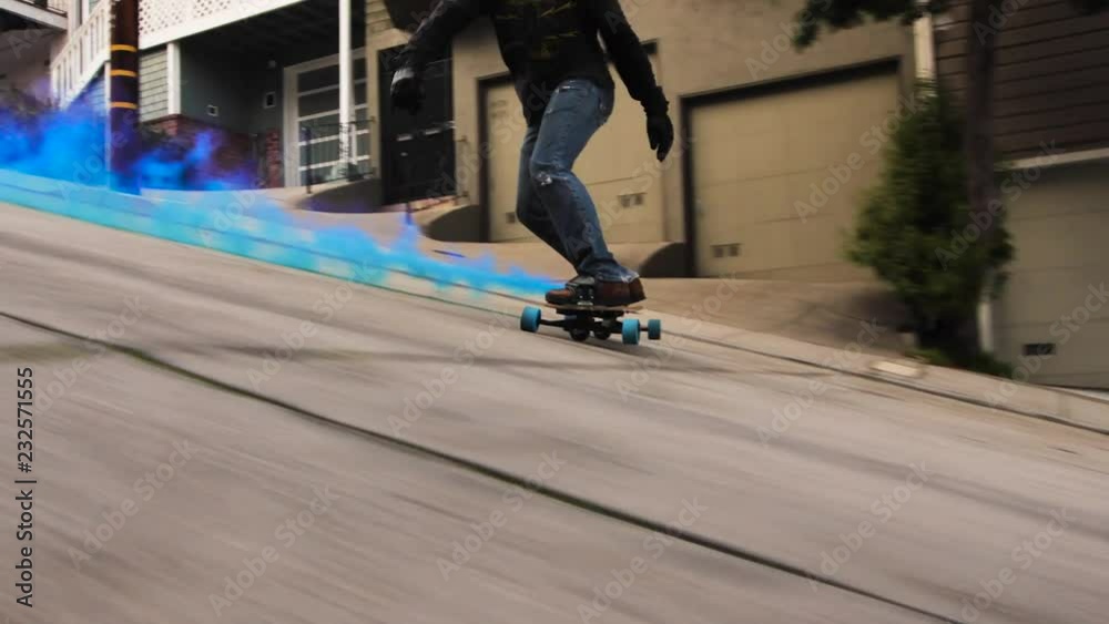Guy skating down hill at super high speed on a longboard with a smoke bomb behind.