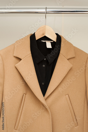 Camel coat with black shirt on a rail