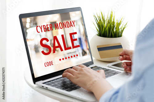 Woman hand holding credit card and tying laptop computer with cyber monday sale on screen device to shopping online, business and technology, digital marketing