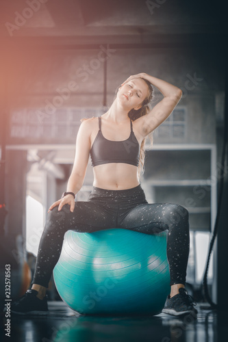 Young attractive woman fitness doing exercises workout on ball in gym. Woman stretching the muscles and relaxing after exercise at fitness gym club.