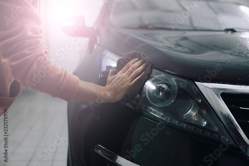 Car detailing - the man holds the microfiber in hand and polishes the car. Selective focus