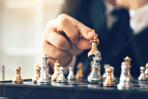 Businessman thinking about strategy concept and hand moving the king in a chess game for win.