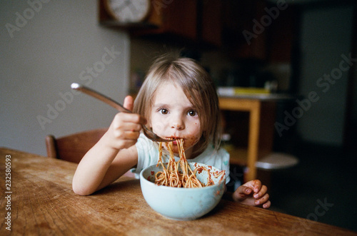 Kid making a mess and eating pasta photo