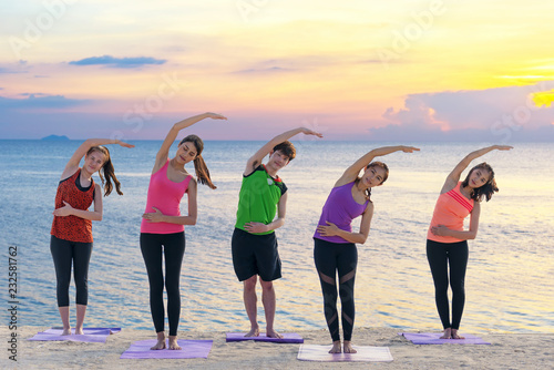 Asian healthy people lifestyle group exercising vital meditate and practicing yoga pose and training class on beach. Healthy and Sport Concept