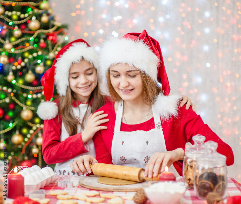Mother and daughter in a Christmas hat prepare festive cookies at home Mother and daughter in a Christmas hat prepare festive cookies at home