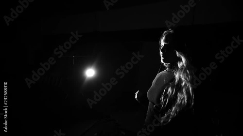 Slow motion shot of girl dancing in dramatic low key light in black and white