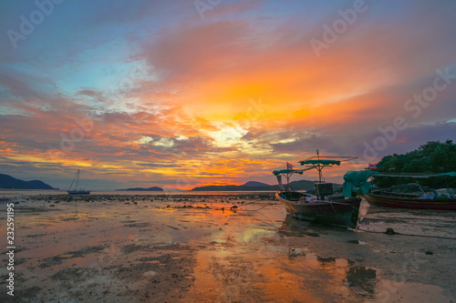 beautiful sunrise above fishing boats on the beach It creates a beautiful reflection in the water..