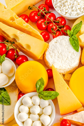 Different dairy products, cheese and cherry tomatoes on white background.