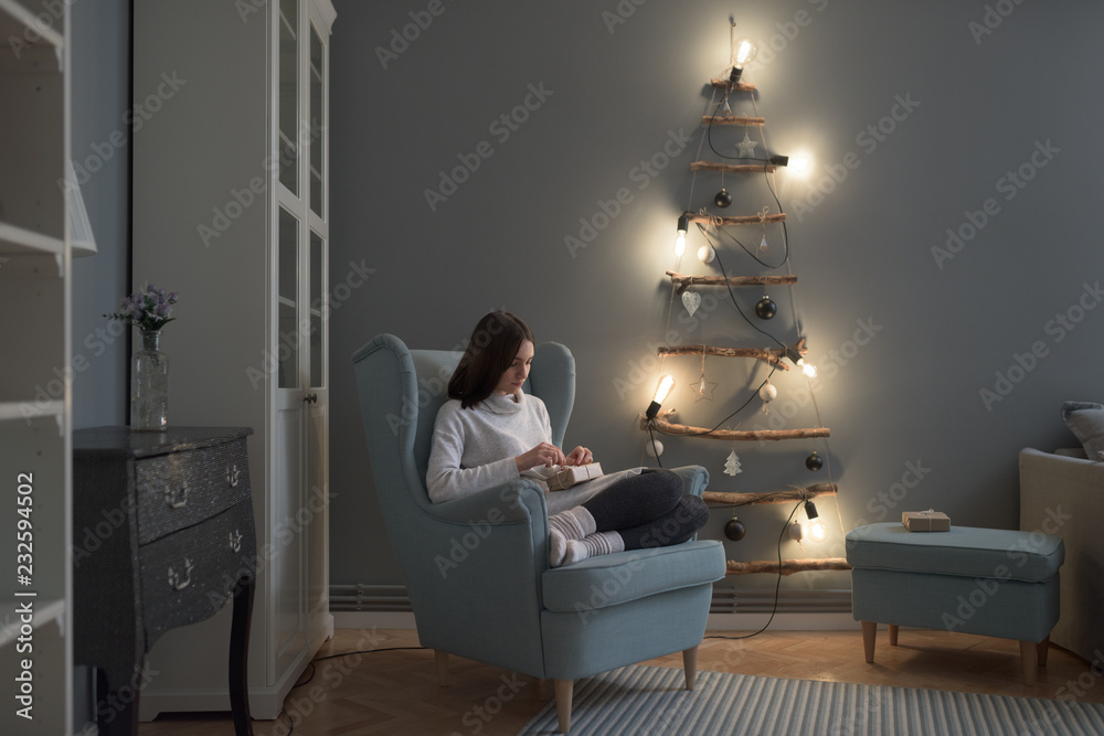 © Stocksy - Beautiful caucasian woman unwrapping Christmas presents