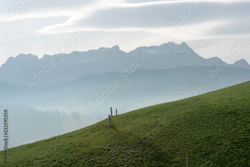 idyllic and peaceful mountain landscape with a wooden fence on a grassy hillside and a great view of the Alpstein mountains and Appenzell region in the Swiss Alps behind photo