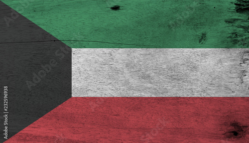 Flag of Kuwait on wooden plate background. Grunge Kuwaiti flag texture, green white and red color with black trapezium based on the hoist side. photo