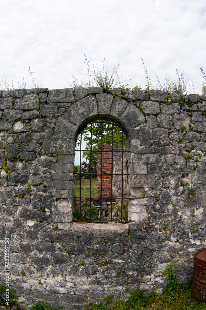 Ancient window with metal bars in a stone house.