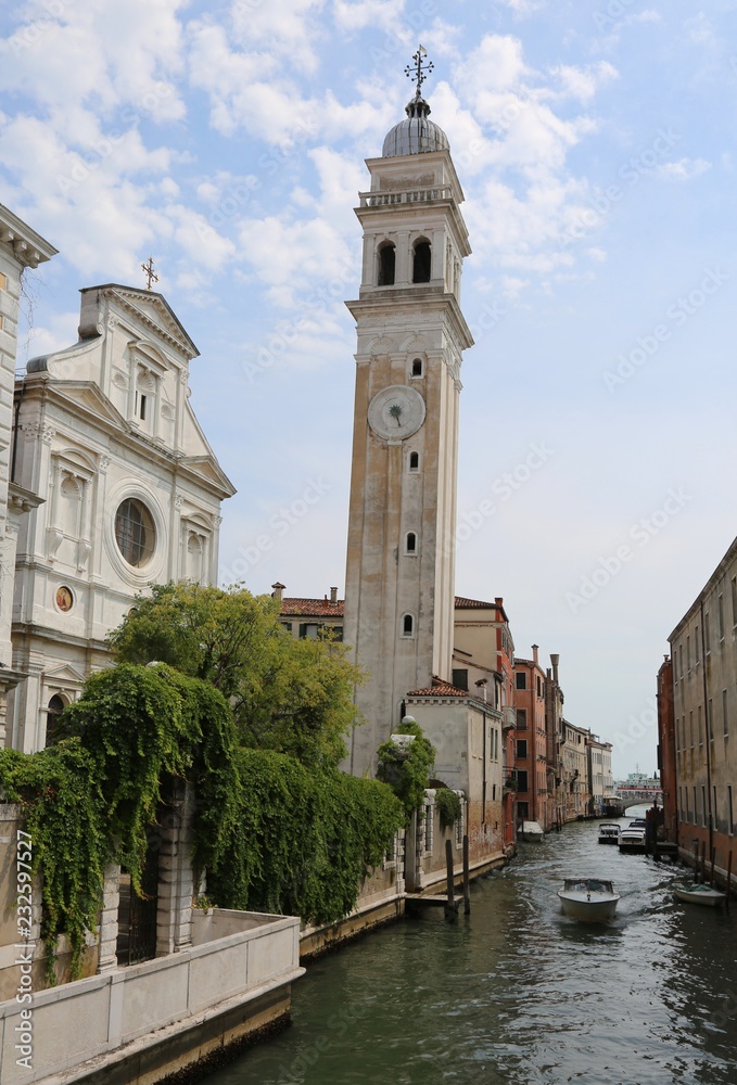 high white bell tower called San Giorgio dei Greci in italian language in Venice in Italy and a boat in the waterway