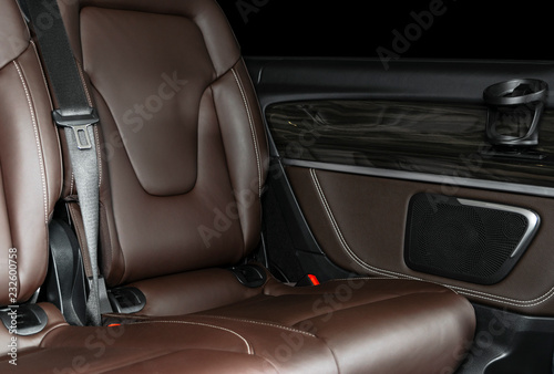 Back passenger seats in modern luxury car. Frontal view. Brown perforated leather with white stitching. Car detailing. Back Leather comfortable orange seats. Car interior details © Aleksei