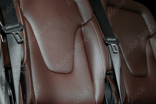 Back passenger seats in modern luxury car. Frontal view. Brown perforated leather with white stitching. Car detailing. Back Leather comfortable orange seats. Car interior details © Aleksei