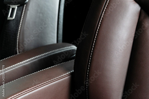 Modern luxury car brown leather interior. Part of leather car seat details with white stitching. Interior of prestige car. Comfortable perforated leather seats. Brown perforated leather. Car detailing