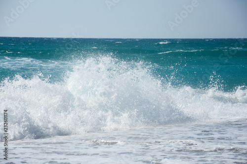 Big breaking wave on a sandy beach. Beautiful sandy beach with big sea waves on sunny summer day