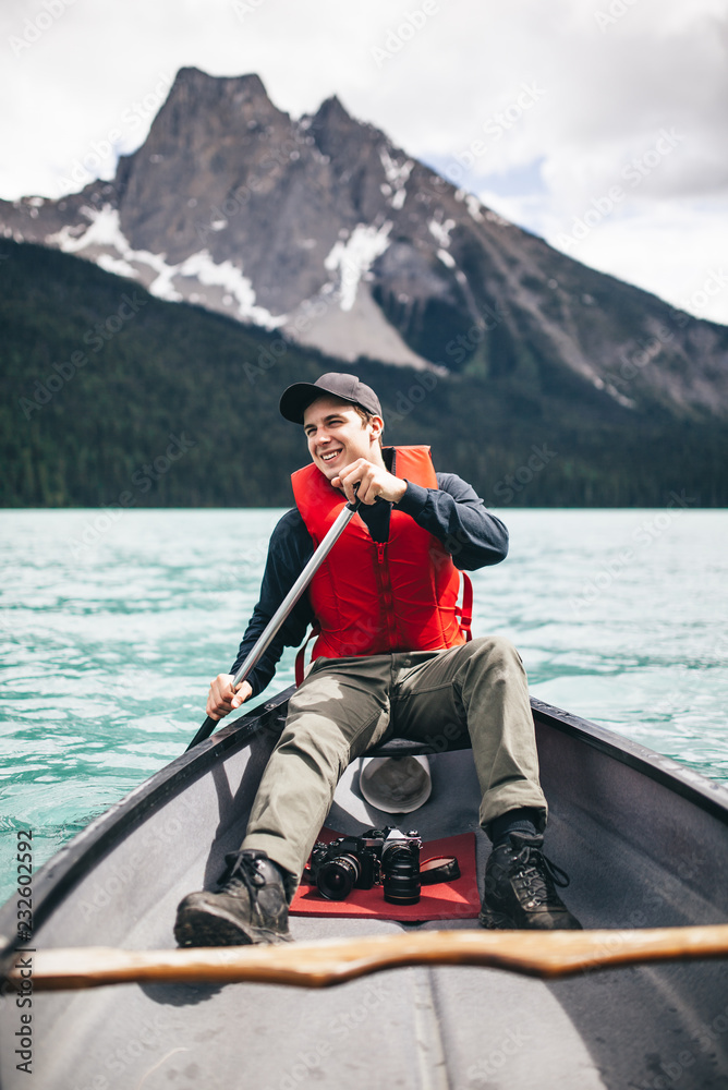 Young Man Rowing a Kayak on a Scenic Lake Young Man Rowing a Kayak on a Scenic Lake
