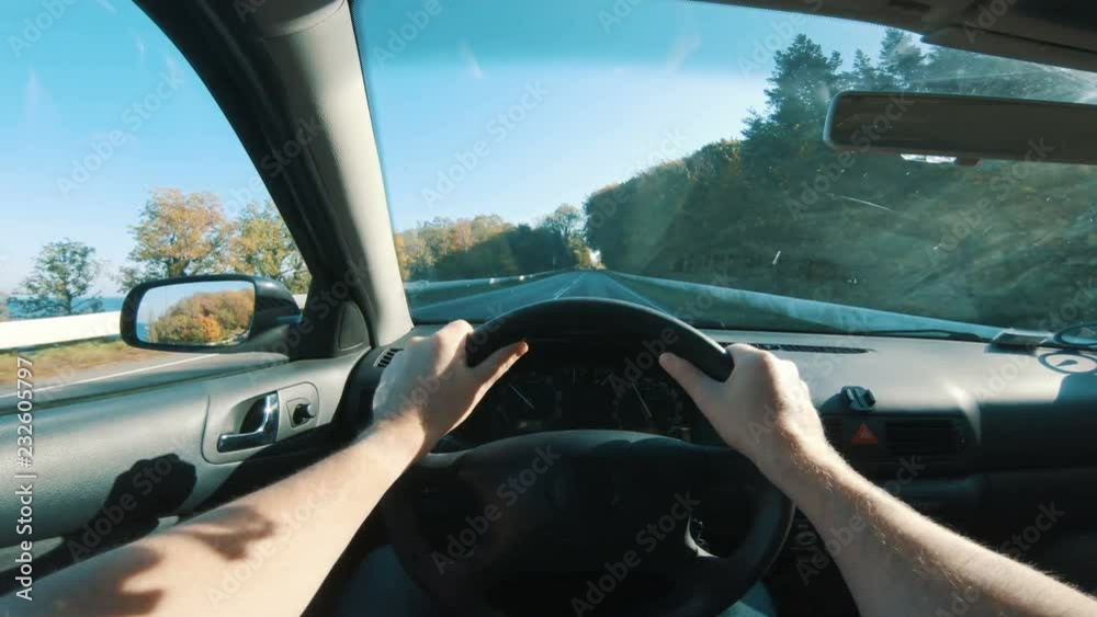 Driver holds both hands on steering wheel as he drives his car