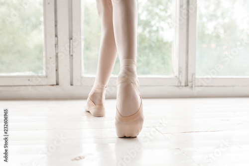 Legs and slippers of classical ballet dancers rehearsing on a light background