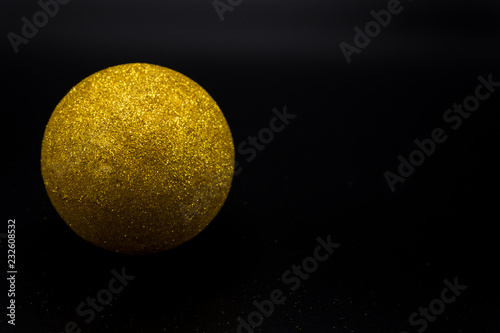 Yellow glittered christmas ball on black background. © Alessandro Vecchi