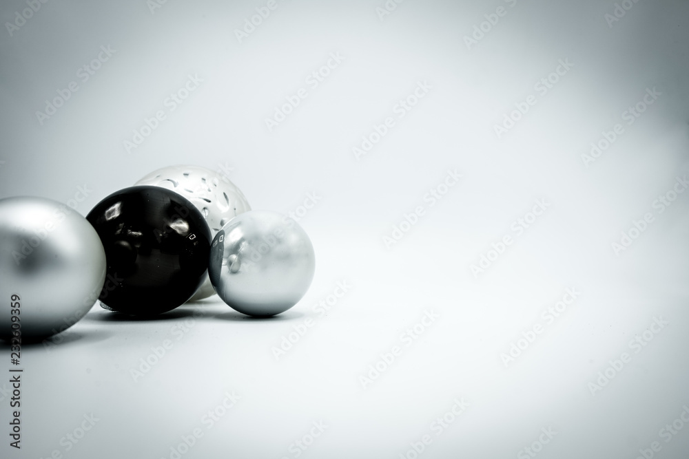 Black and silver Christmas baubles on white with vignette.