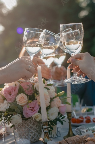 Hands holding the glasses of champagne or white wine making a toast at a wedding