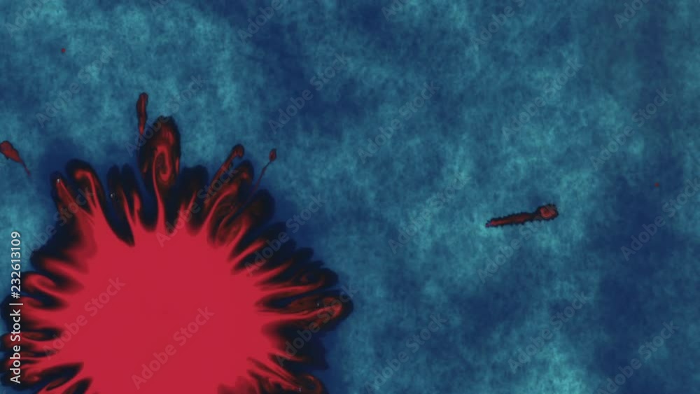 Slow motion bright red ink drop on blue ink colored wet paper