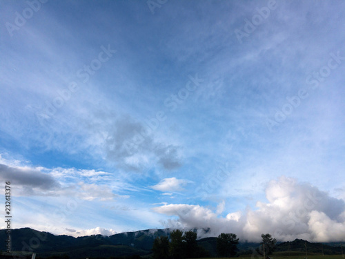 Idyllic mountain scenery with fir trees, blue sky and clouds 