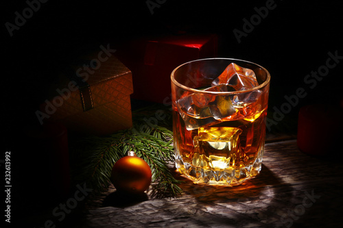 Glass with cognac or whiskey, Christmas balls and candles. New Year's tree, balls and glass with alcohol.