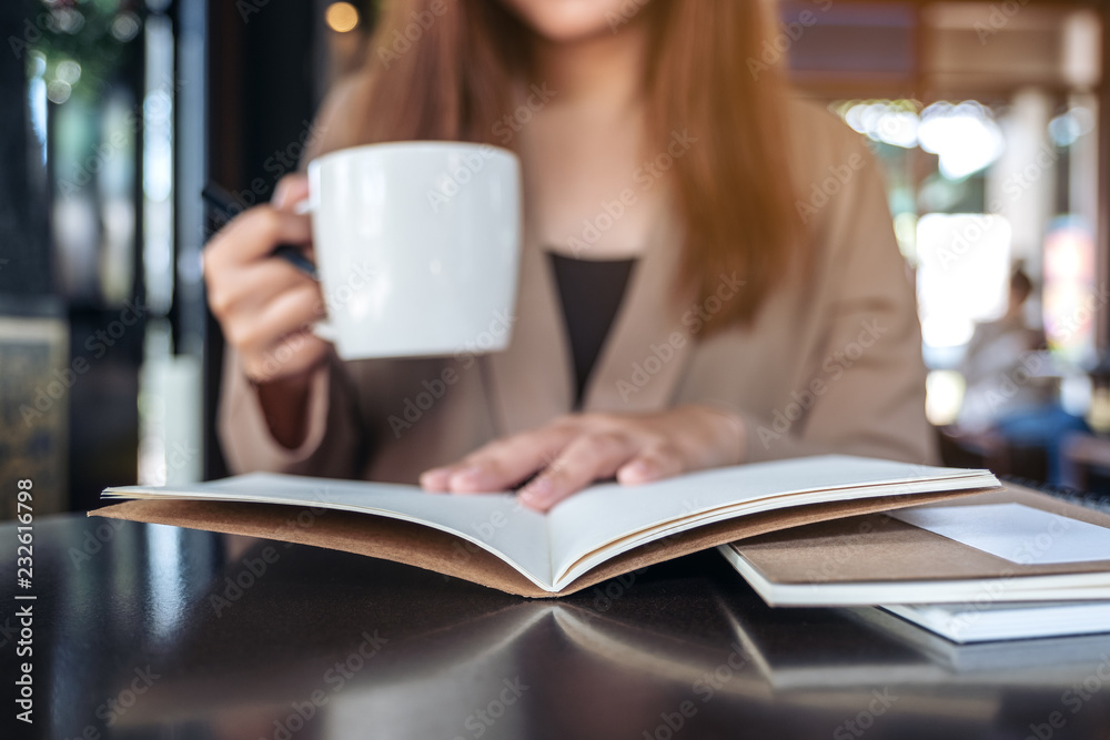 Closeup image of a woman reading and opening a book while drinking coffee in cafe Closeup image of a woman reading and opening a book while drinking coffee in cafe