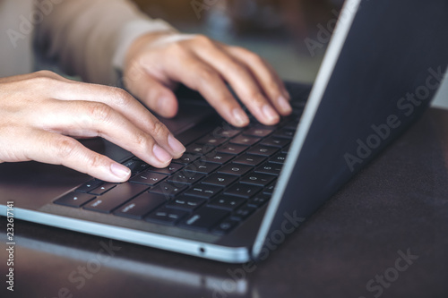 Closeup image of hands using and typing on laptop keyboard on table