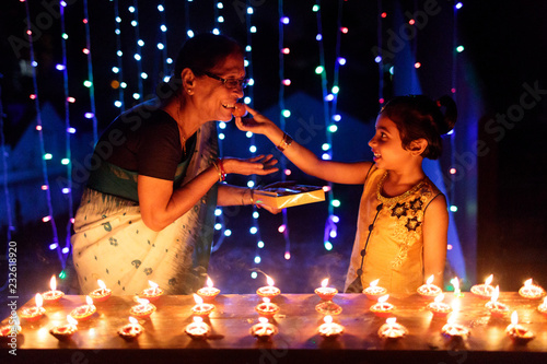 Little girl and her grandmother celebrating diwali with sweets photo