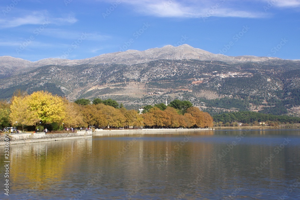 People walk at the park of pamvotis lake in city of Ioannina in Epirus Greece at autumn, minaret and the museum at the background