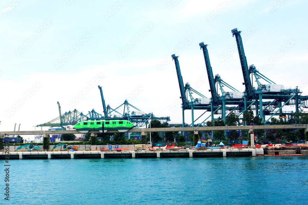 a light train passing  heavy equipment near harbour