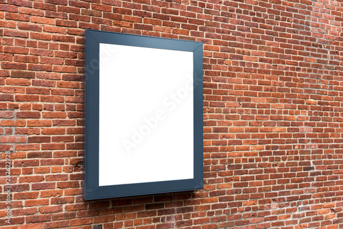 Blank advertising poster board on the brick wall on street..