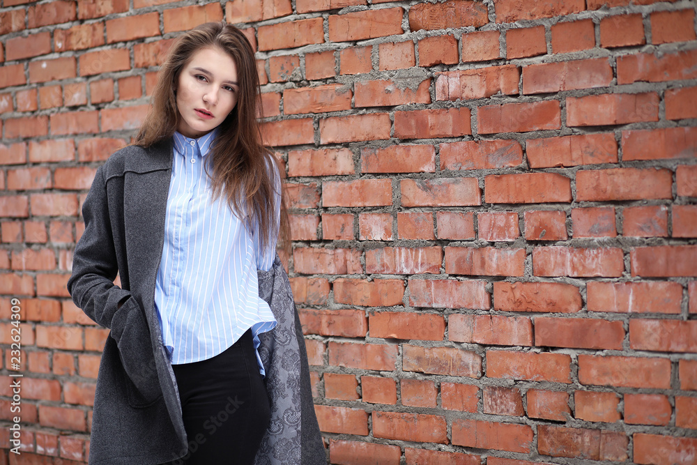 Young beautiful girl near red brick wall posing