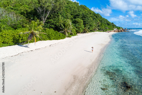 A woman strolling along Anse Fourmis beach. La Digue, Seychelles, Africa photo