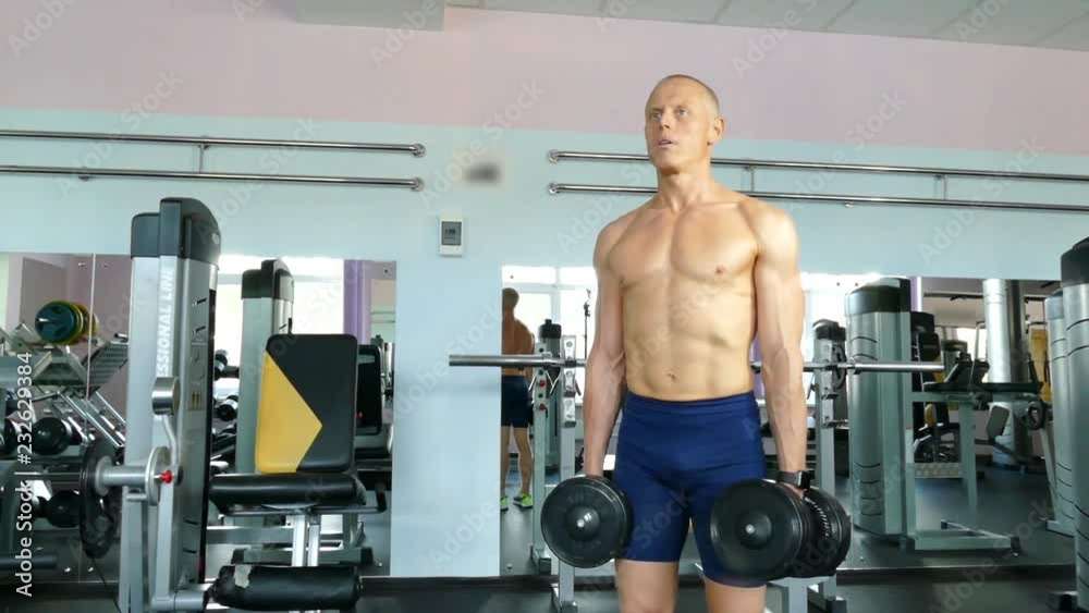 sportsman is standing and raising dumbbells. a healthy lifestyle sportsman is standing and raising dumbbells. a healthy lifestyle